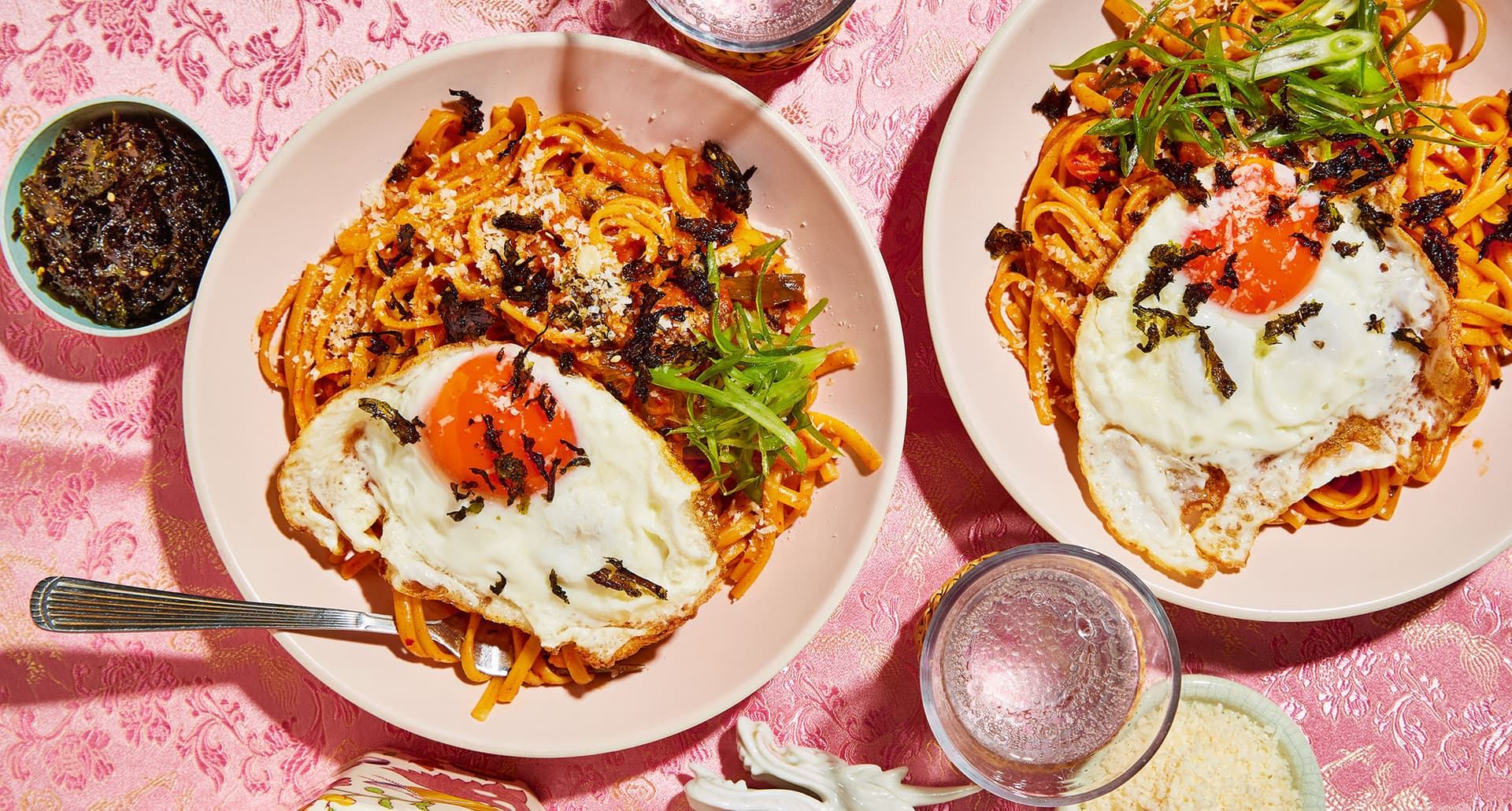 easy september dinners: two plates of cheesy kimchi linguine with gochujang butter, topped with scallions, crispy seaweed and fried eggs
