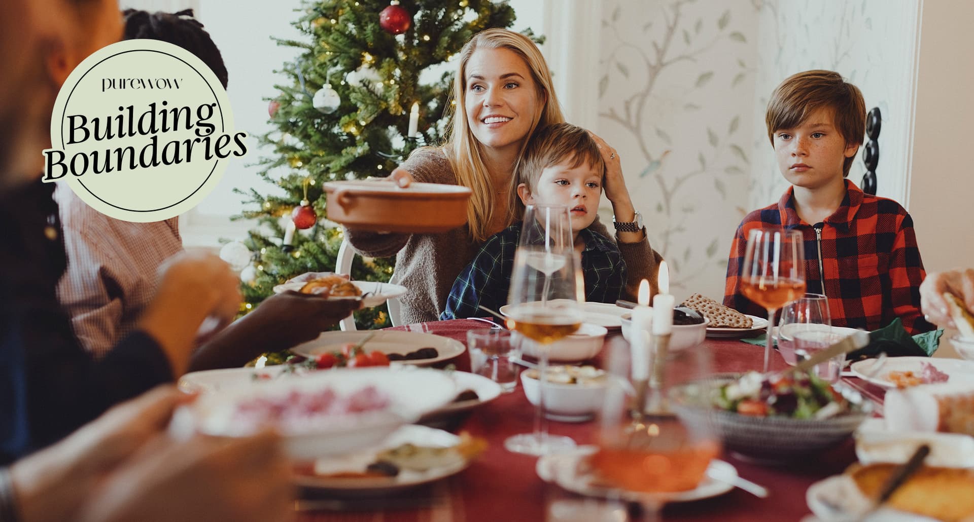 A mom holding a child in front of christmas tree passes a tray around