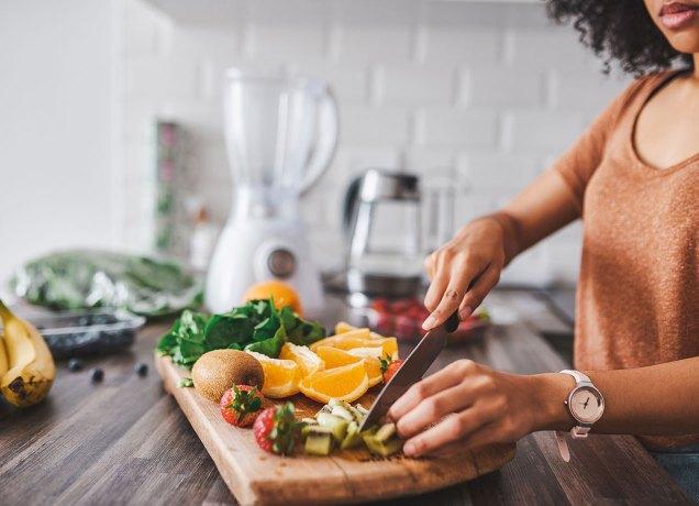 low sugar fruits: two hands cutting fruit on a wooden cutting board