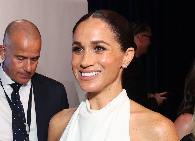 Meghan-Markle-Surprise-Hamptons-Trip-G9-Ventures-Summit: A photo of Meghan Markle at an award ceremony. She wears a white halter neck dress and has her slicked back in a bun.