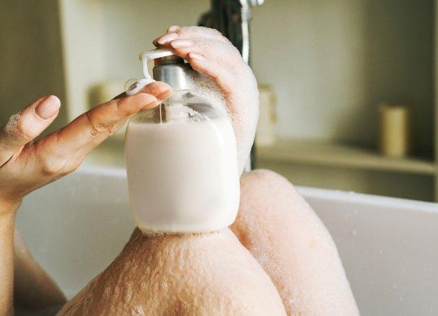 best feminine wash products a close up photo of a woman's hand and a bottle in a tub