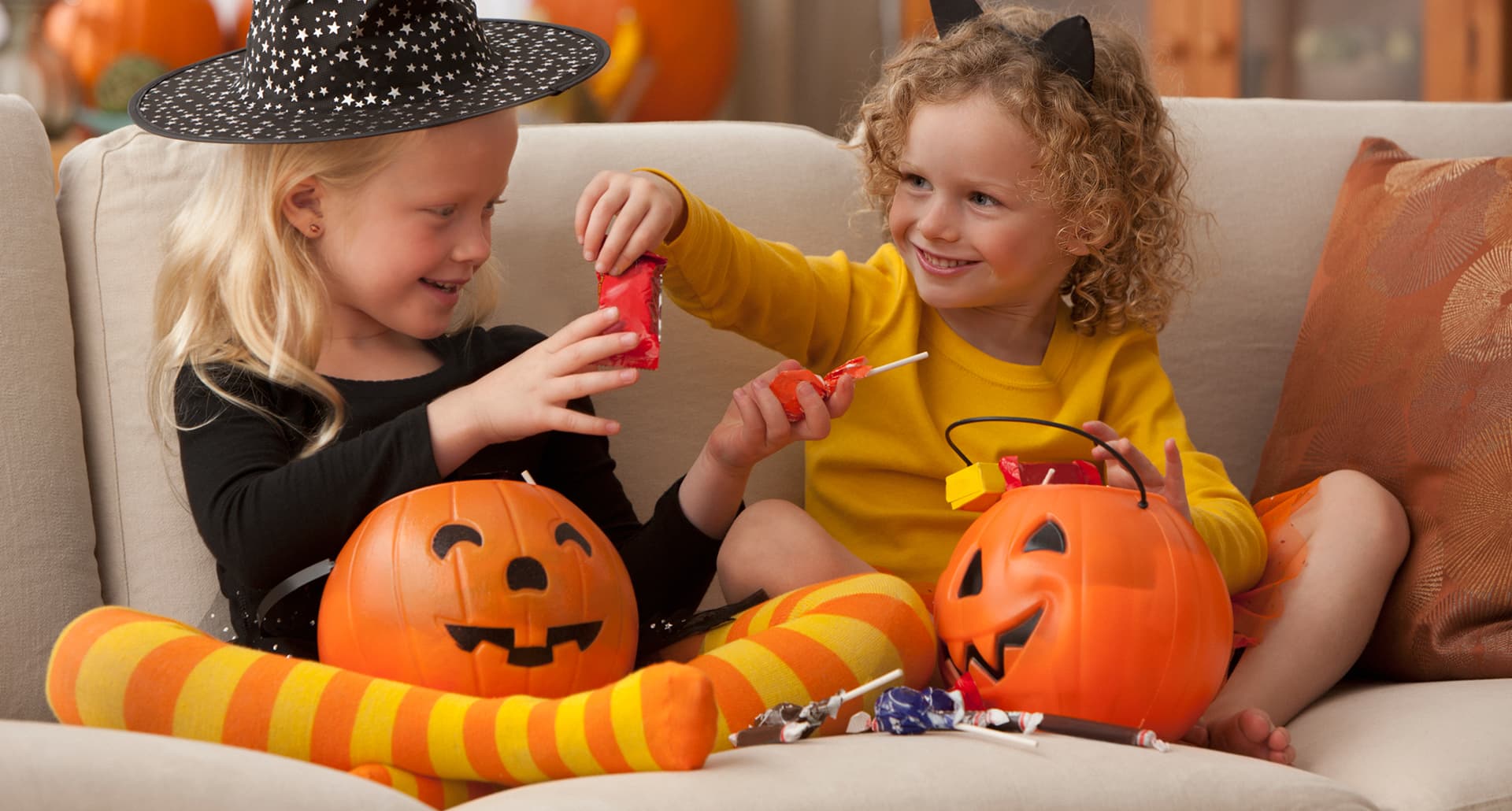 two kids sharing halloween candy out of pumpkin buckets