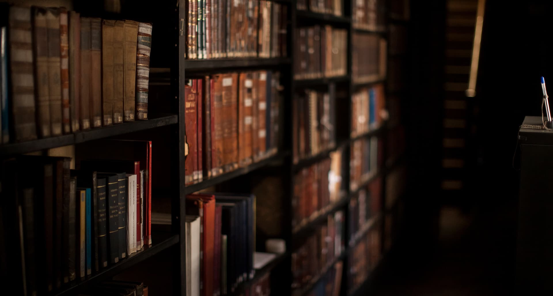 dark academia books: a dark library with shelves of old books