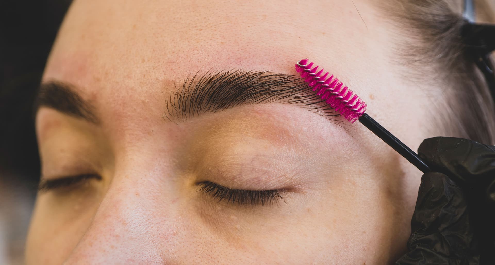 eyebrow treatments a woman brushing her brows with a spoolie